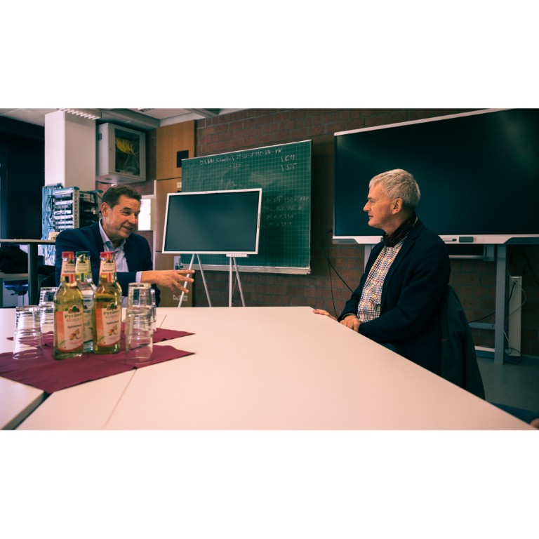 2 Personen sitzen in Klassenzimmer und unterhalten sich